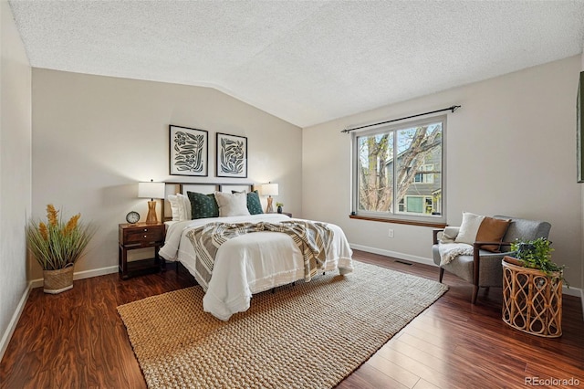 bedroom featuring a textured ceiling, baseboards, wood finished floors, lofted ceiling, and visible vents