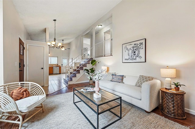 living area with baseboards, a chandelier, wood finished floors, and stairway