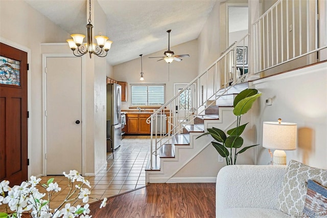 entrance foyer with stairway, baseboards, ceiling fan with notable chandelier, and lofted ceiling