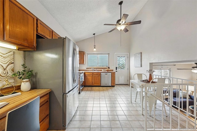 kitchen with a ceiling fan, appliances with stainless steel finishes, brown cabinets, and light countertops