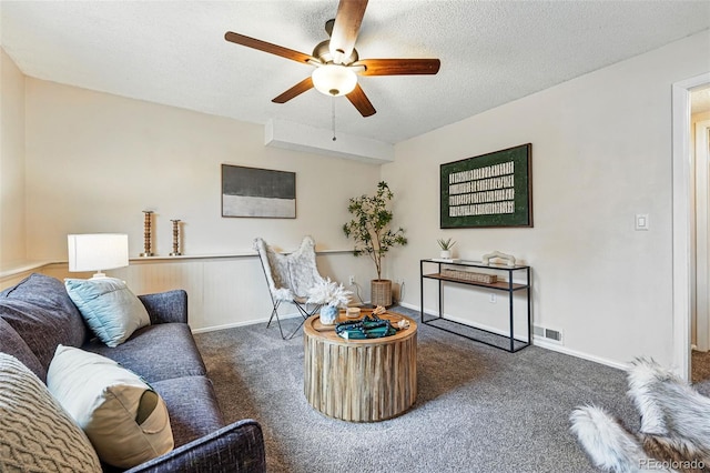living area featuring visible vents, baseboards, ceiling fan, a textured ceiling, and carpet