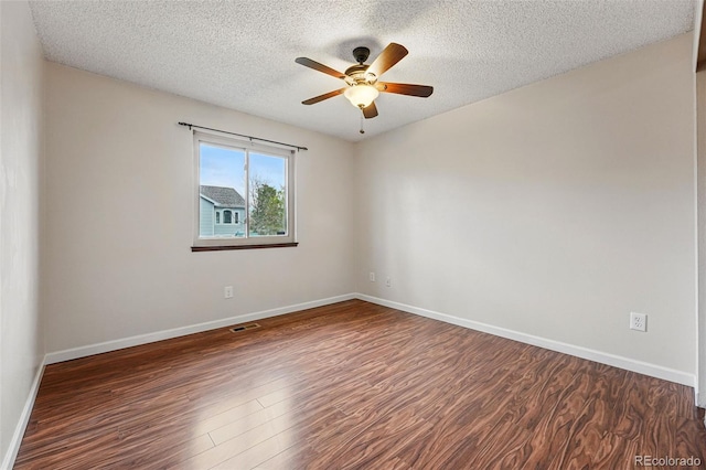 spare room with a ceiling fan, a textured ceiling, visible vents, baseboards, and dark wood-style floors