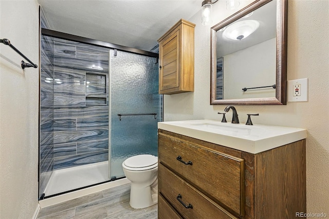 full bath with vanity, a stall shower, toilet, and wood finished floors