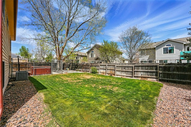 view of yard featuring a fenced backyard, central AC, and a residential view