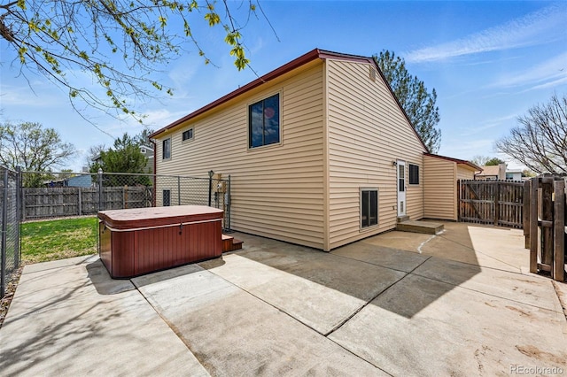 rear view of house with a fenced backyard, a patio, and a hot tub