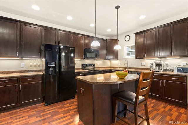 kitchen featuring dark hardwood / wood-style flooring, a breakfast bar, black appliances, a center island, and hanging light fixtures