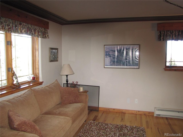 living room featuring a healthy amount of sunlight, baseboard heating, hardwood / wood-style flooring, and ornamental molding