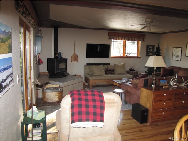 living room featuring a wood stove, ceiling fan, and light hardwood / wood-style flooring