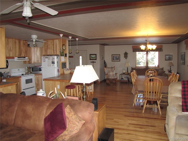 dining space with light wood-type flooring, beam ceiling, sink, and ceiling fan with notable chandelier