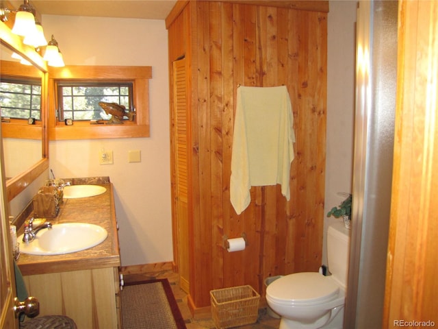 bathroom with vanity, wood walls, and toilet