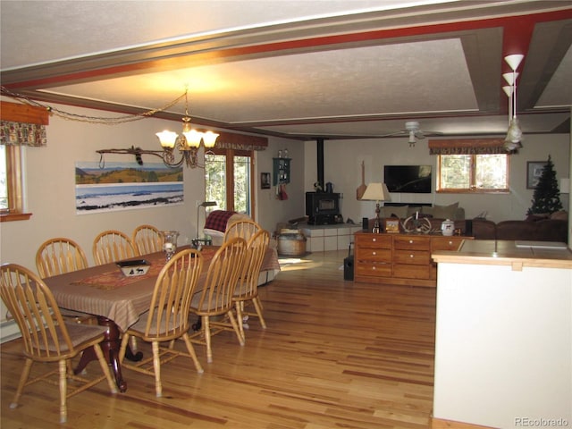 dining space with a wood stove, an inviting chandelier, a healthy amount of sunlight, and light hardwood / wood-style flooring