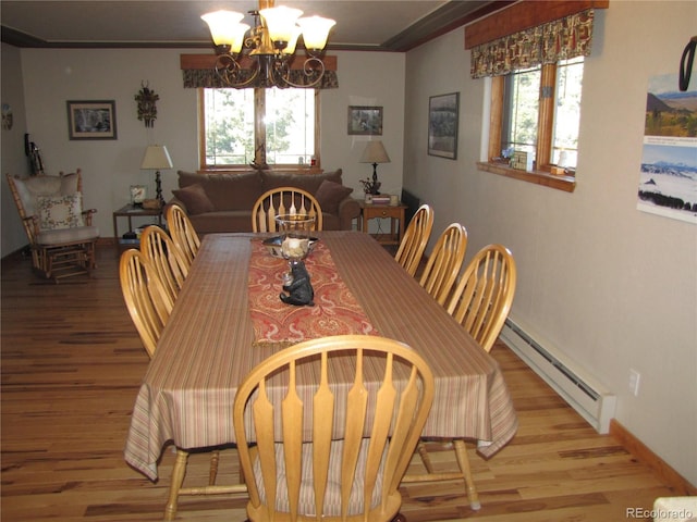 105 Ladigo Ln, Hartsel, CO 80449 - dining area featuring a baseboard heating unit, wood finished floors, a chandelier, crown molding, and baseboards
