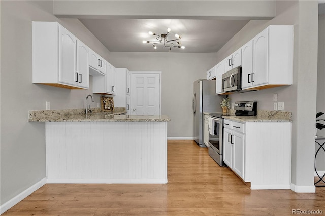 kitchen featuring light stone countertops, baseboards, a peninsula, an inviting chandelier, and stainless steel appliances