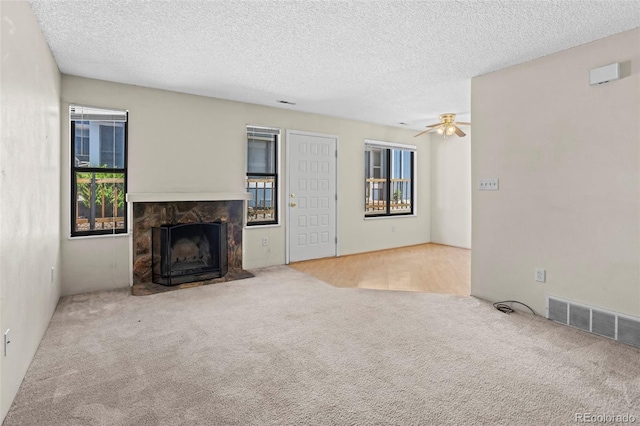 2638 Hearthwood Ln, Colorado Springs, CO 80917 - unfurnished living room with a textured ceiling, carpet floors, a fireplace with flush hearth, a ceiling fan, and healthy amount of natural light
