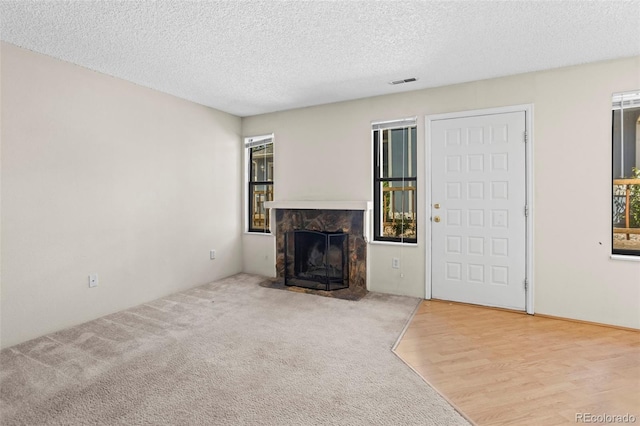 2638 Hearthwood Ln, Colorado Springs, CO 80917 - unfurnished living room with a stone fireplace, a textured ceiling, carpet floors, and wood finished floors