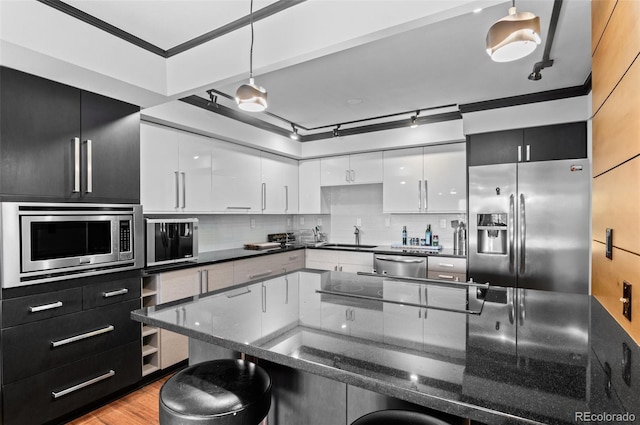 kitchen with appliances with stainless steel finishes, a breakfast bar, decorative light fixtures, sink, and white cabinets