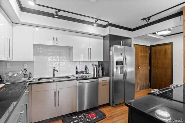 kitchen with sink, white cabinetry, tasteful backsplash, light wood-type flooring, and appliances with stainless steel finishes