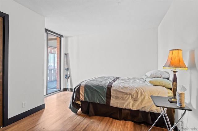 bedroom with hardwood / wood-style floors, floor to ceiling windows, and access to outside