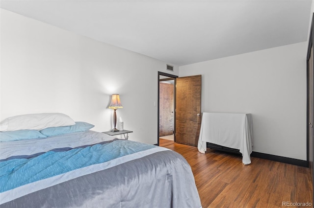 bedroom with dark hardwood / wood-style flooring