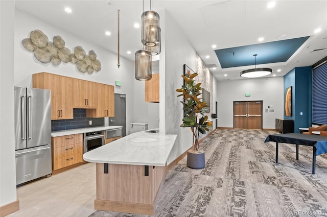 kitchen featuring stainless steel appliances, hanging light fixtures, a high ceiling, and a breakfast bar area