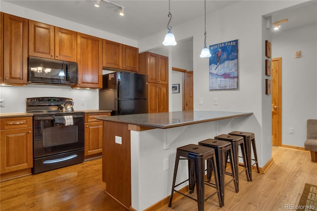 801 Trailhead Cir Unit 812, Winter Park, CO 80482 - kitchen featuring black appliances, a kitchen breakfast bar, light wood-style floors, and brown cabinetry