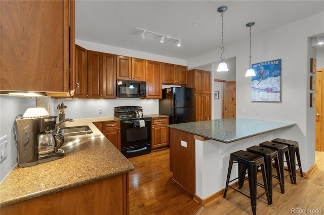 801 Trailhead Cir Unit 812, Winter Park, CO 80482 - kitchen featuring black appliances, a peninsula, wood finished floors, brown cabinetry, and a breakfast bar area