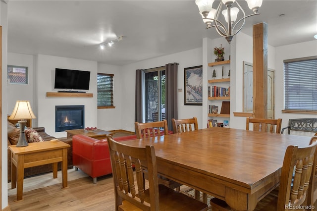 801 Trailhead Cir Unit 812, Winter Park, CO 80482 - dining room featuring light wood-style flooring, a glass covered fireplace, a chandelier, and rail lighting