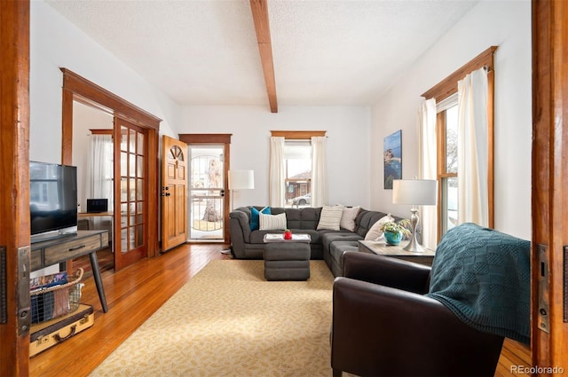 living room with a textured ceiling, light hardwood / wood-style flooring, and beamed ceiling