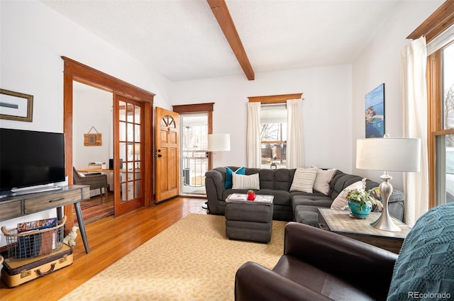 living room featuring a textured ceiling, light hardwood / wood-style floors, french doors, and beamed ceiling