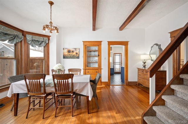 dining area featuring an inviting chandelier, wood-type flooring, beam ceiling, and a textured ceiling