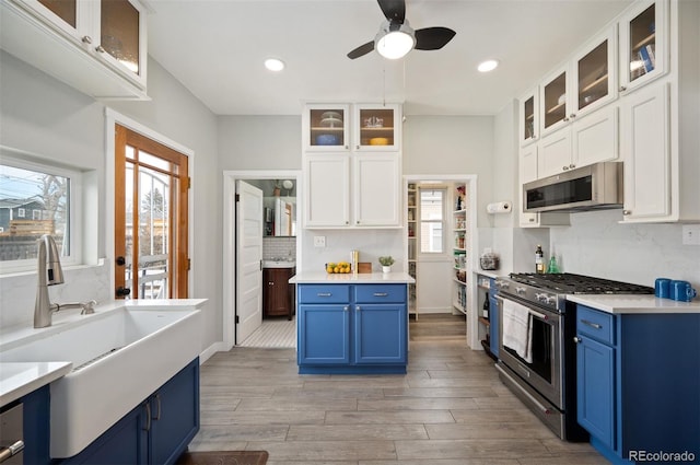 kitchen featuring sink, blue cabinetry, white cabinets, and appliances with stainless steel finishes