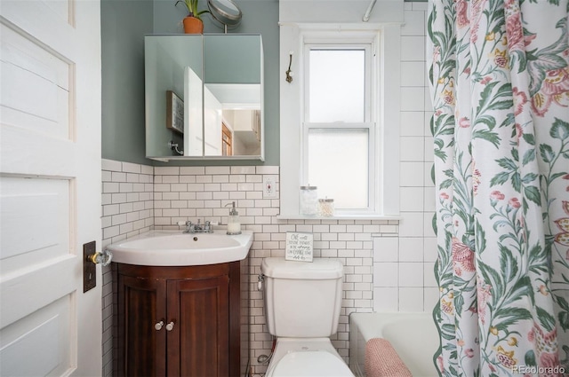 bathroom with vanity, toilet, and tile walls