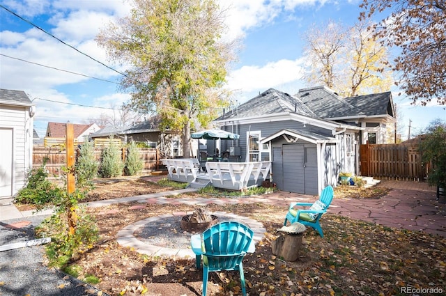 back of property with a storage shed, a patio area, a deck, and an outdoor fire pit