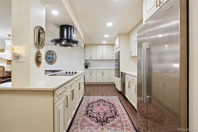 kitchen featuring dark wood-style floors, stainless steel appliances, tasteful backsplash, light countertops, and wall chimney exhaust hood