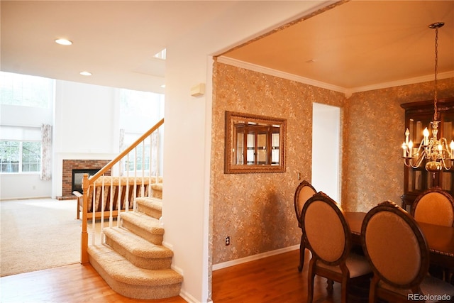 dining area with a fireplace, hardwood / wood-style floors, ornamental molding, and an inviting chandelier