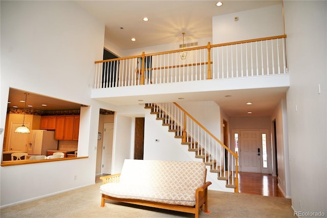 stairs featuring carpet flooring and a high ceiling