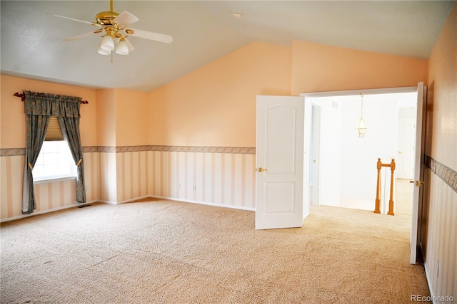 empty room with carpet floors, vaulted ceiling, and ceiling fan