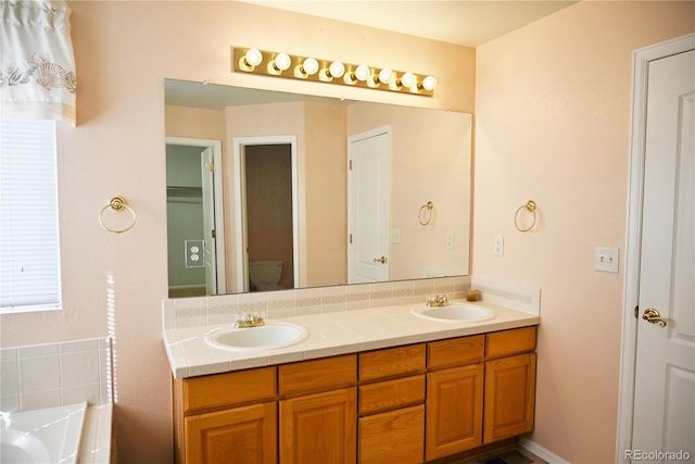 bathroom with vanity, a bath, and toilet