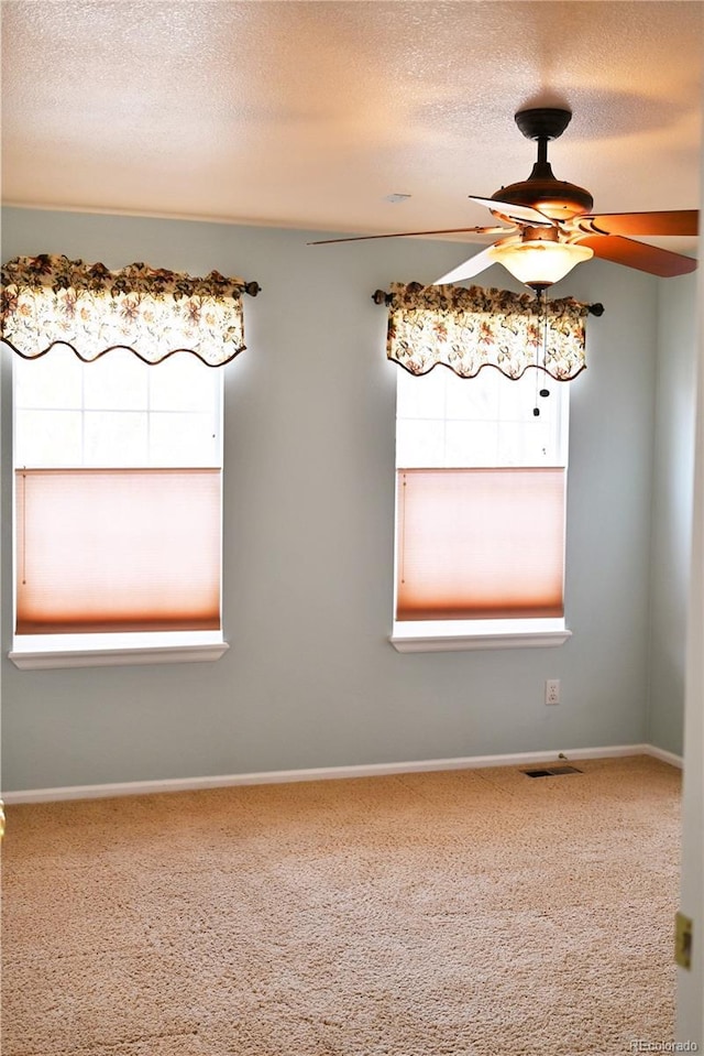 empty room featuring carpet, ceiling fan, and a textured ceiling