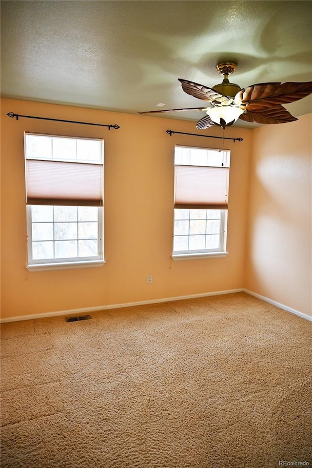 carpeted empty room with a textured ceiling, a wealth of natural light, and ceiling fan