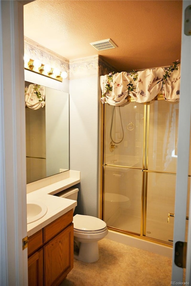 bathroom with toilet, vanity, a textured ceiling, and walk in shower