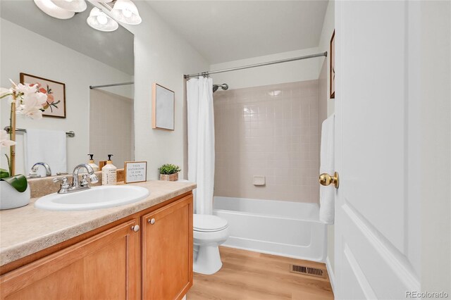 full bathroom featuring toilet, vanity, shower / bath combo, wood finished floors, and visible vents
