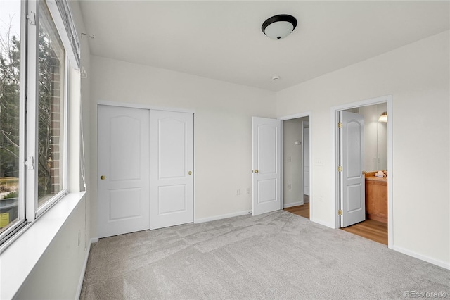 unfurnished bedroom featuring ensuite bathroom, baseboards, a closet, and carpet