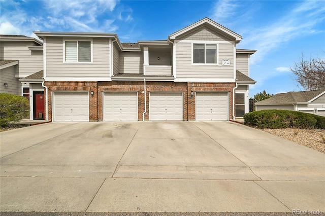 multi unit property featuring a garage, brick siding, and concrete driveway