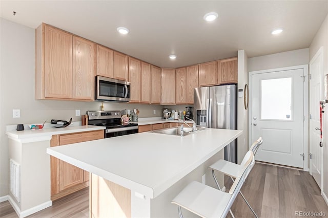 kitchen featuring stainless steel appliances, an island with sink, sink, and a kitchen bar