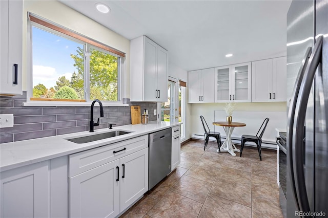 kitchen with appliances with stainless steel finishes, white cabinetry, sink, and tile patterned flooring