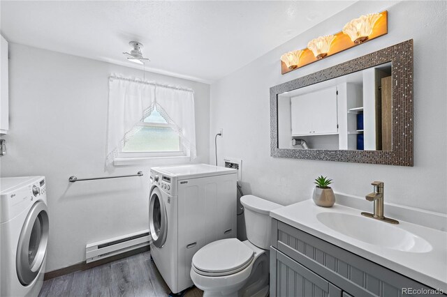 bathroom with toilet, baseboard heating, hardwood / wood-style floors, and washer and dryer