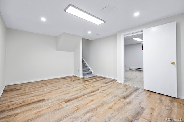 basement with a baseboard radiator and light hardwood / wood-style floors