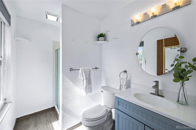 bathroom with wood-type flooring, toilet, walk in shower, and vanity