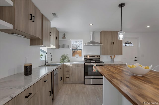 kitchen featuring stainless steel appliances, pendant lighting, sink, wall chimney range hood, and butcher block counters